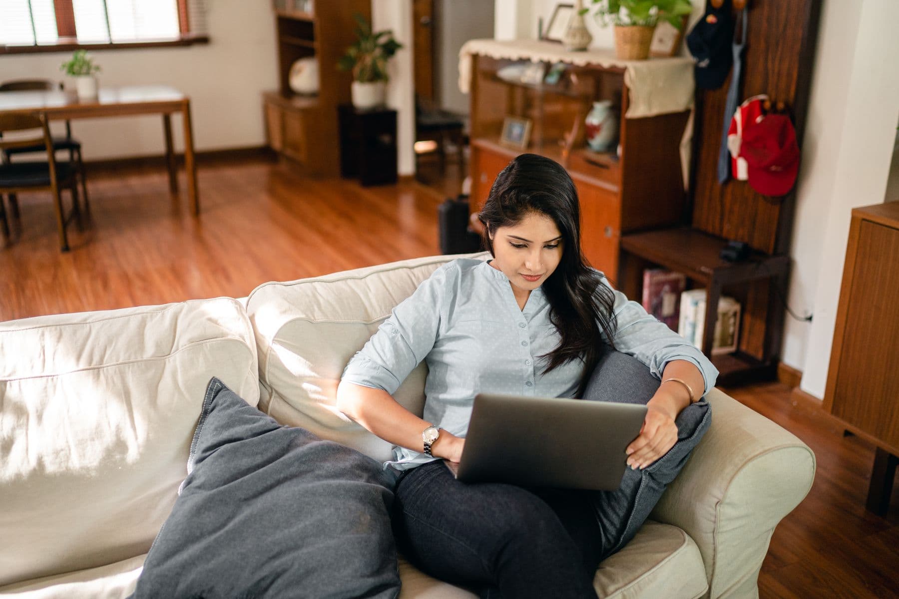 Indian woman using a laptop on a sofa at home